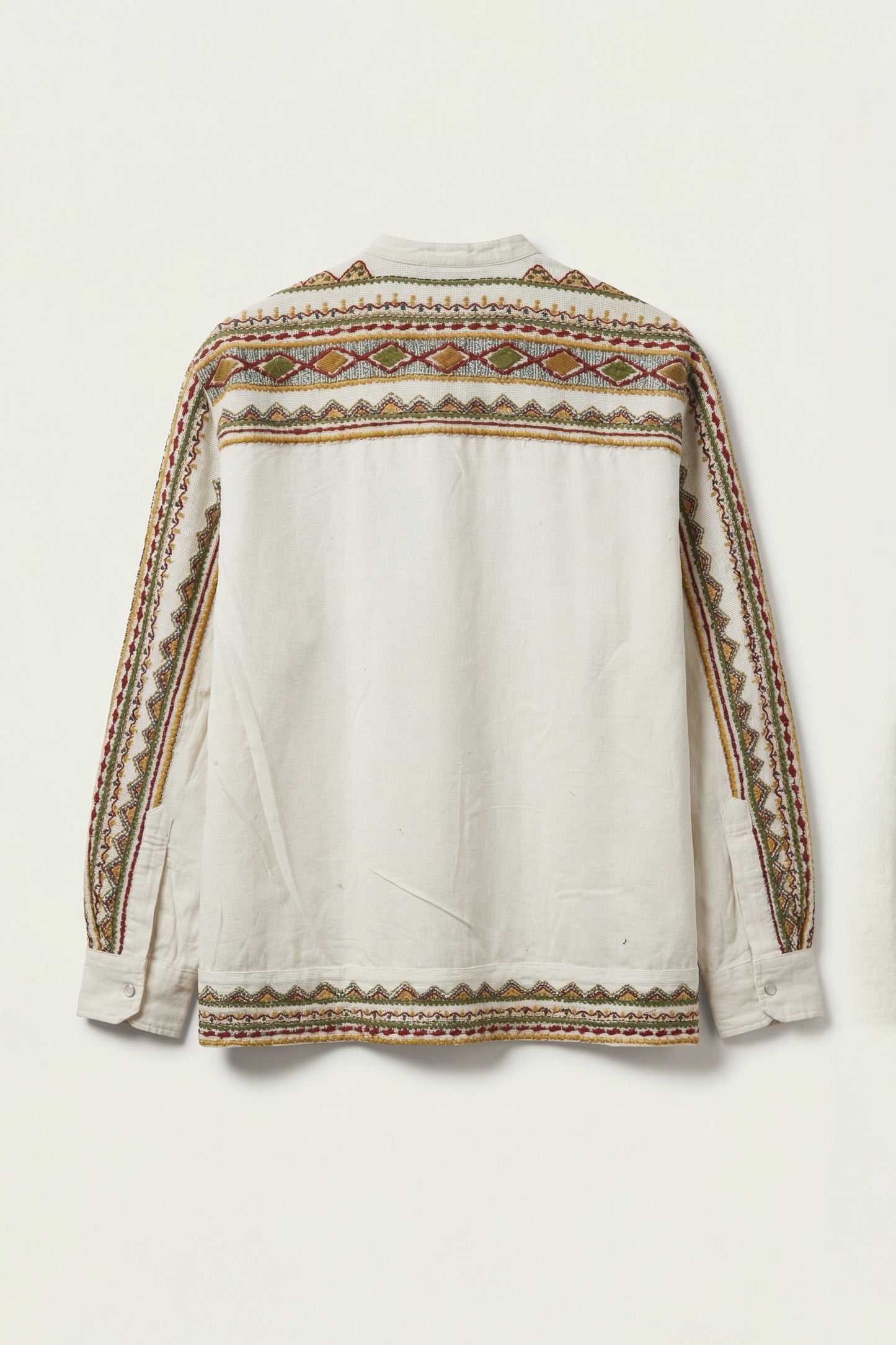 White blouse with intricate brown and beige embroidery on a light background