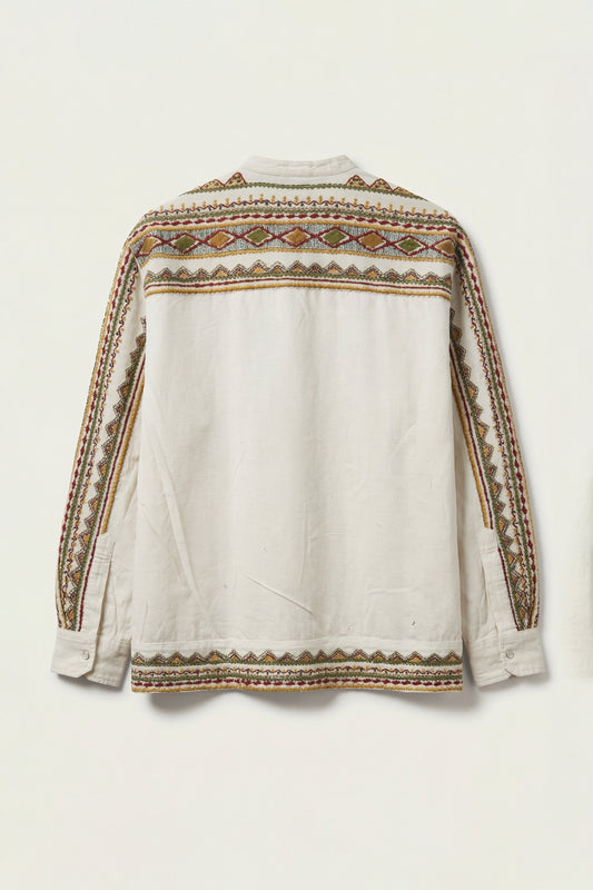 White blouse with intricate brown and beige embroidery on a light background