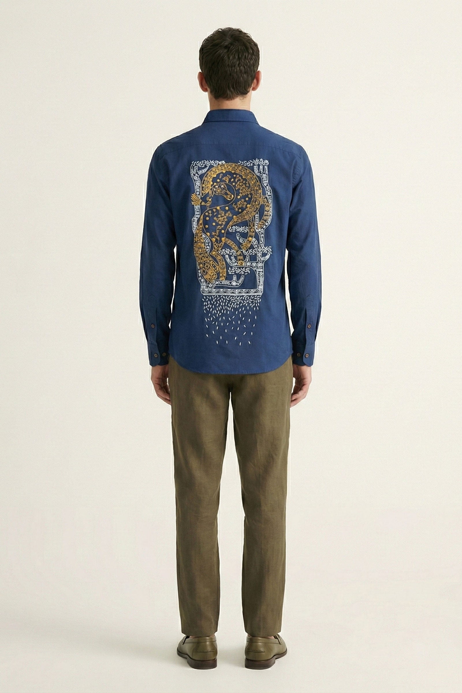 Man wearing a blue shirt with a graphic design on the back, standing against a plain background