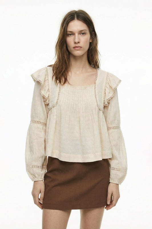 Woman wearing a beige blouse with ruffled details and a brown skirt on a white background