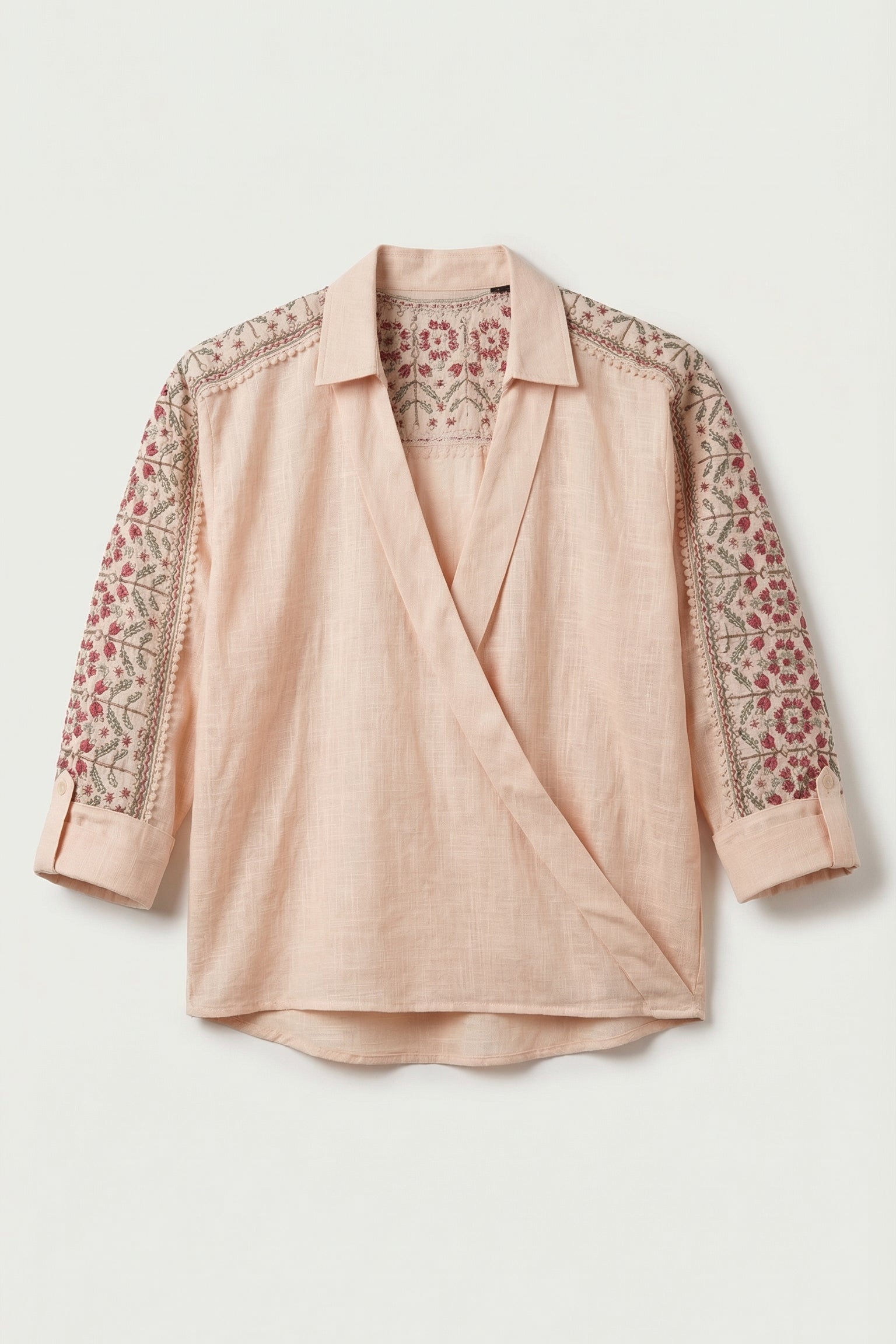 Pink blouse with floral embroidery on sleeves against a light background