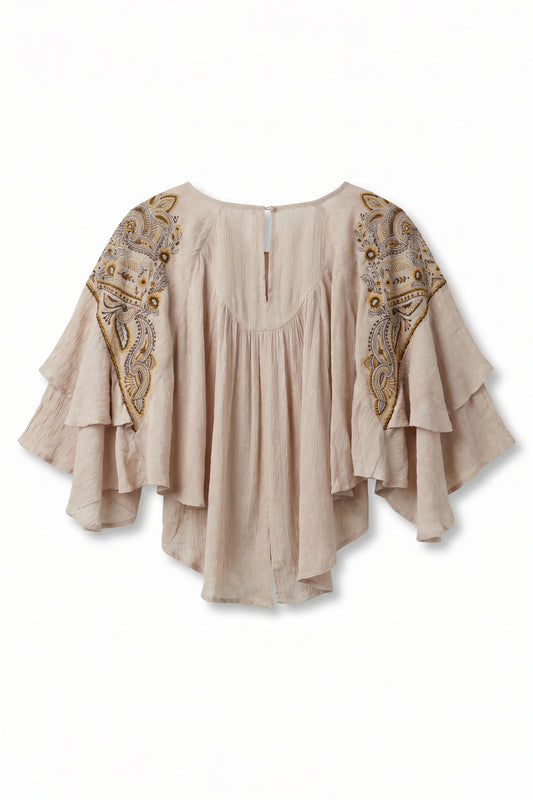 Beige blouse with intricate gold patterns on a white background