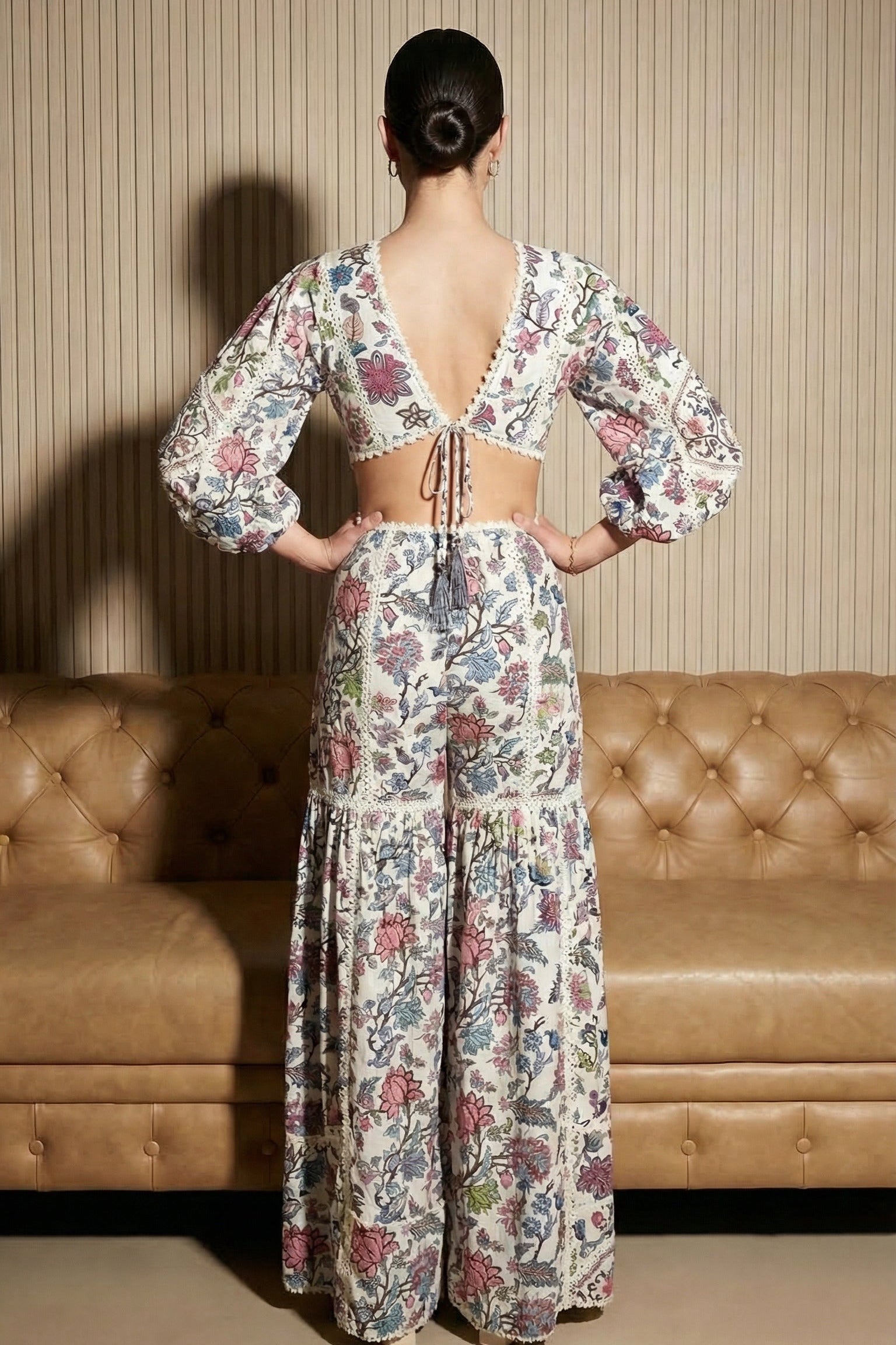 Woman wearing a floral dress standing in front of a beige sofa.