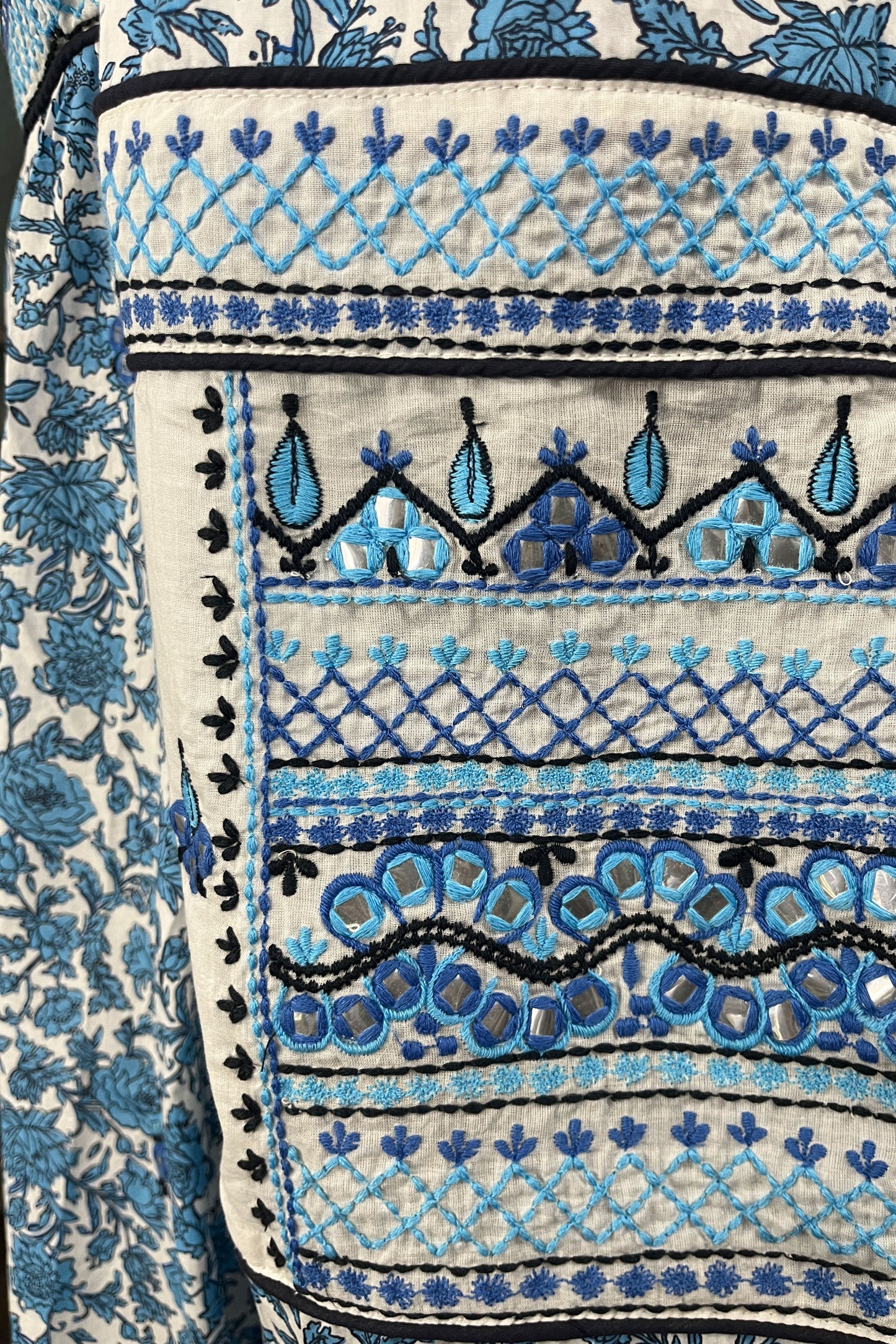 Close-up of a fabric with blue and black embroidery on a white background