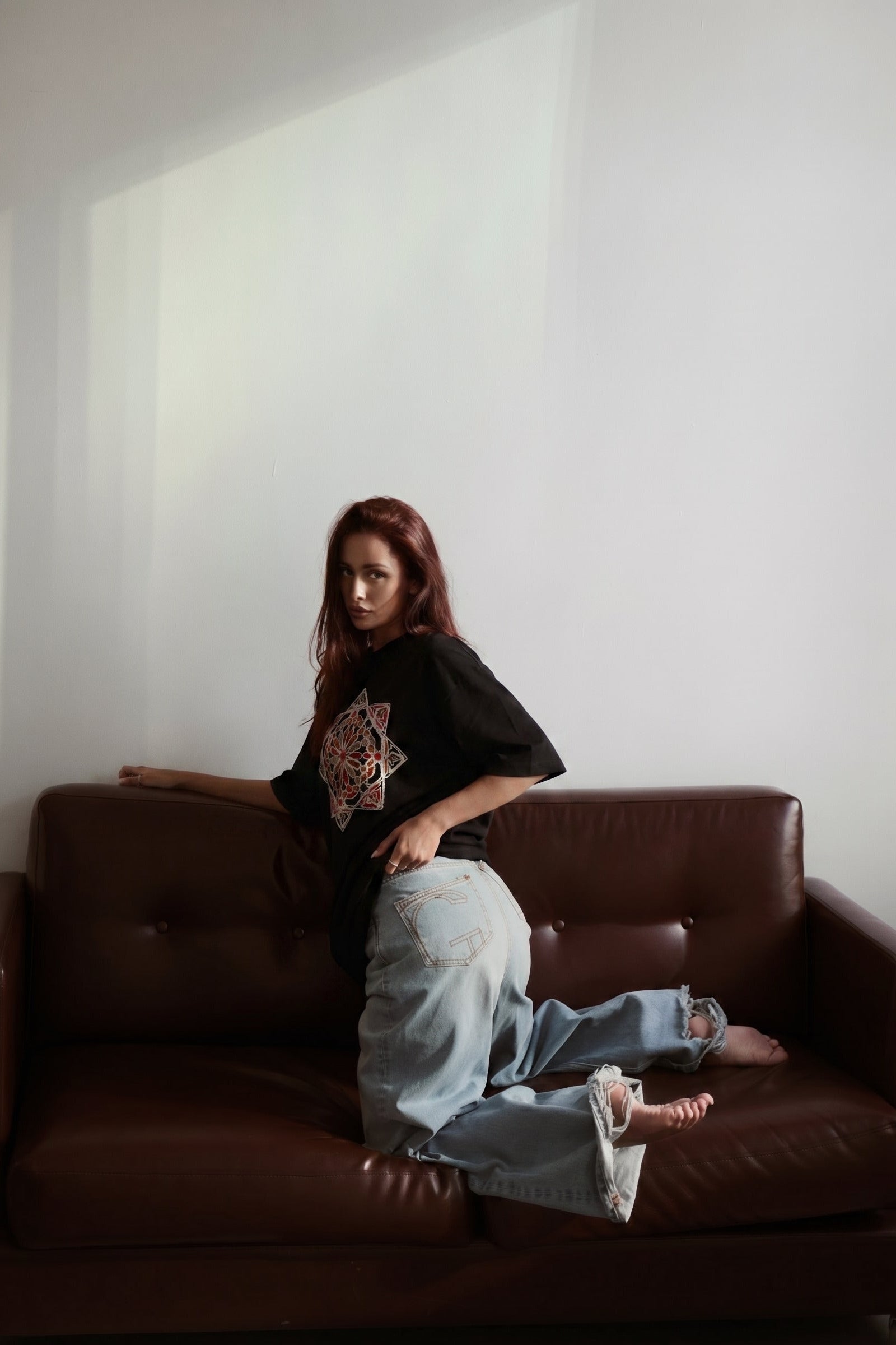 Person sitting on a brown leather couch in a minimalistic room.