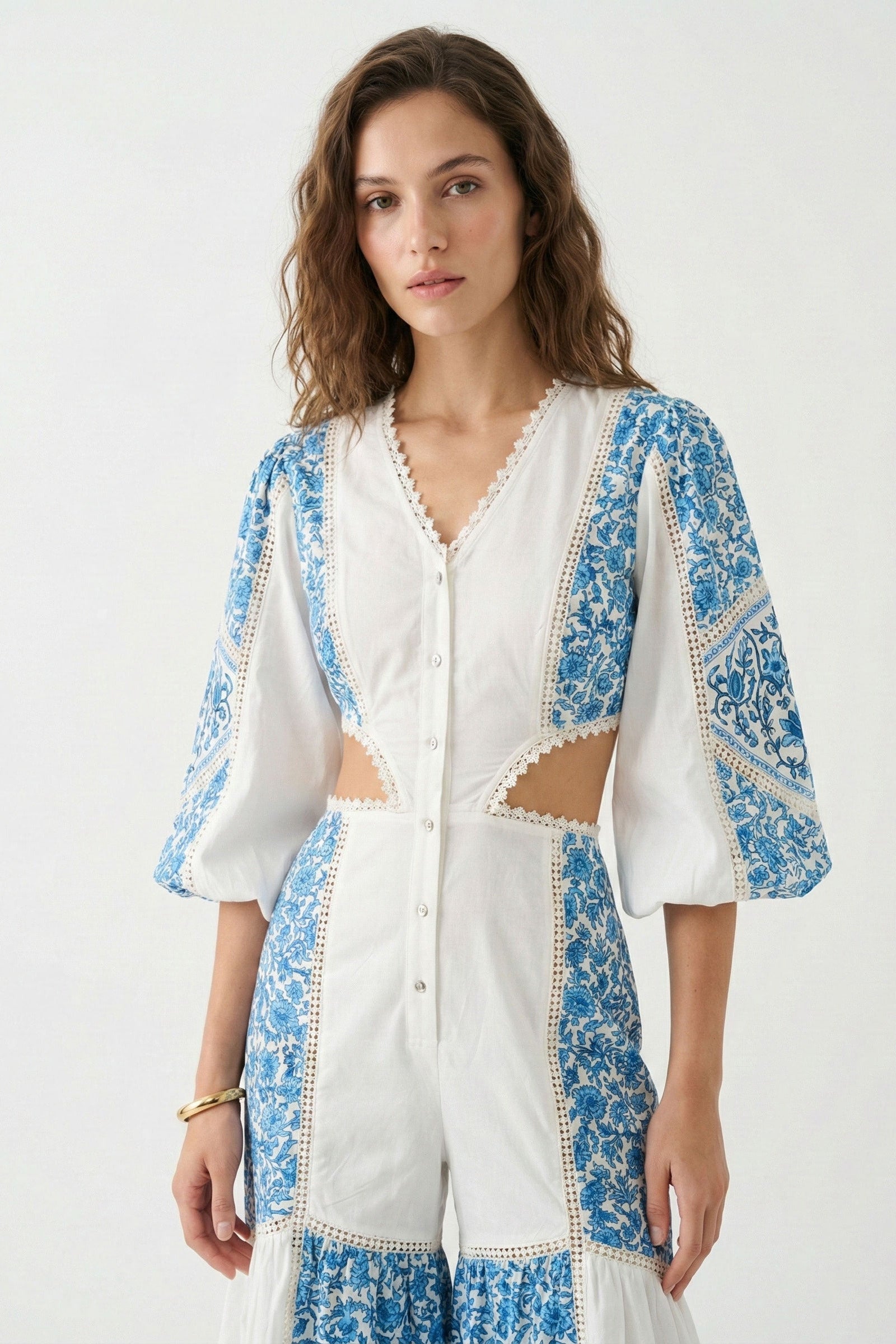 Woman wearing a white and blue embroidered dress on a white background