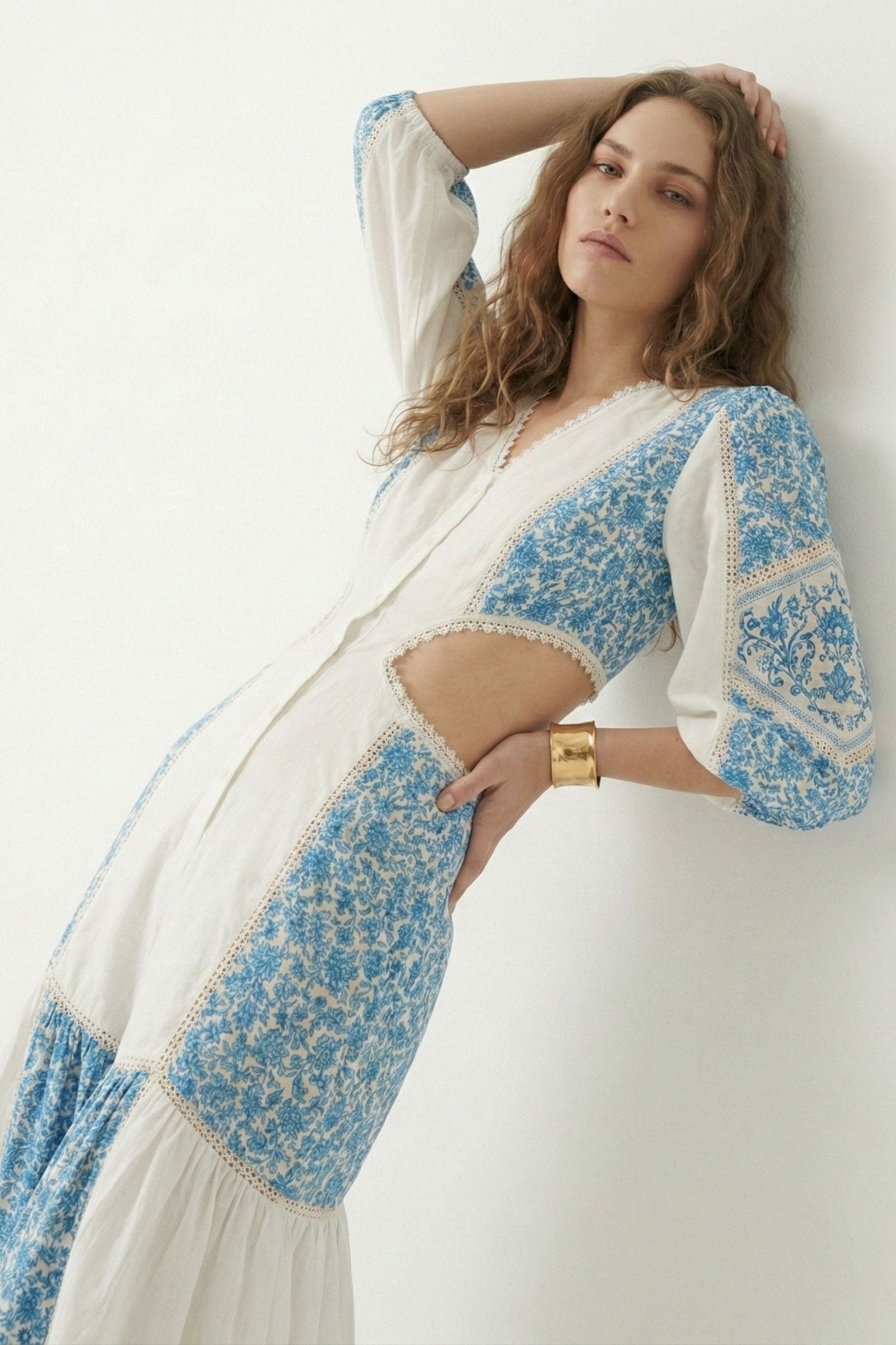 Woman wearing a white and blue floral dress against a white background