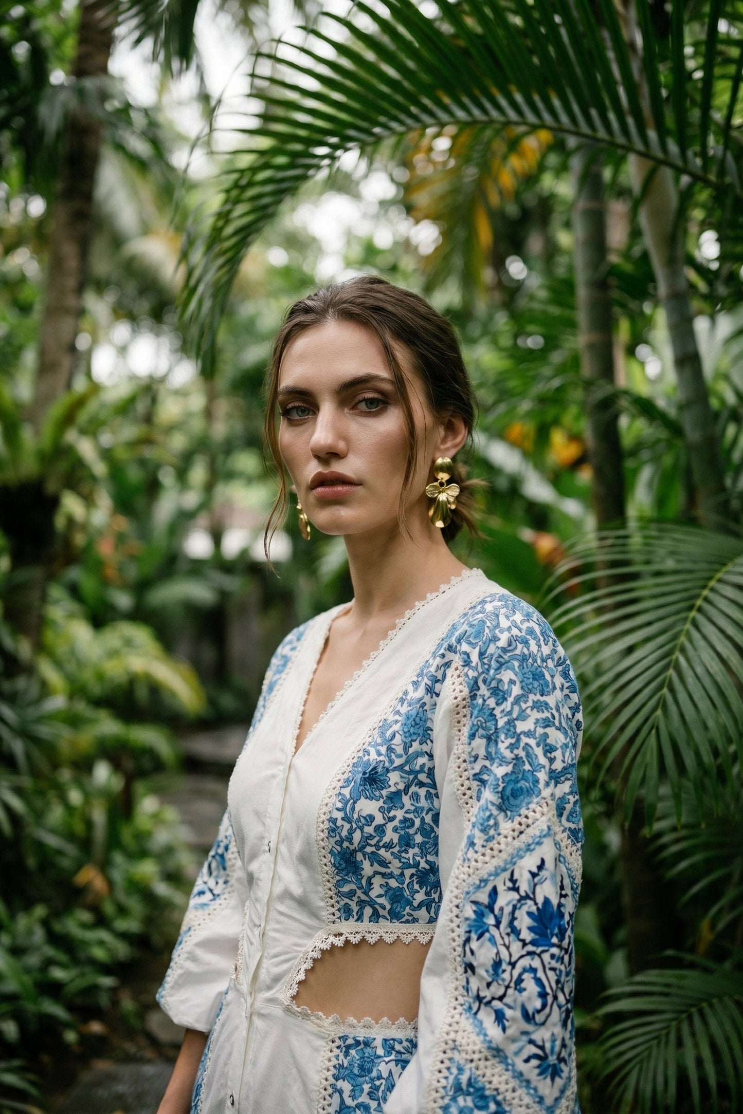 Woman wearing a blue and white floral embroidered outfit in a tropical setting