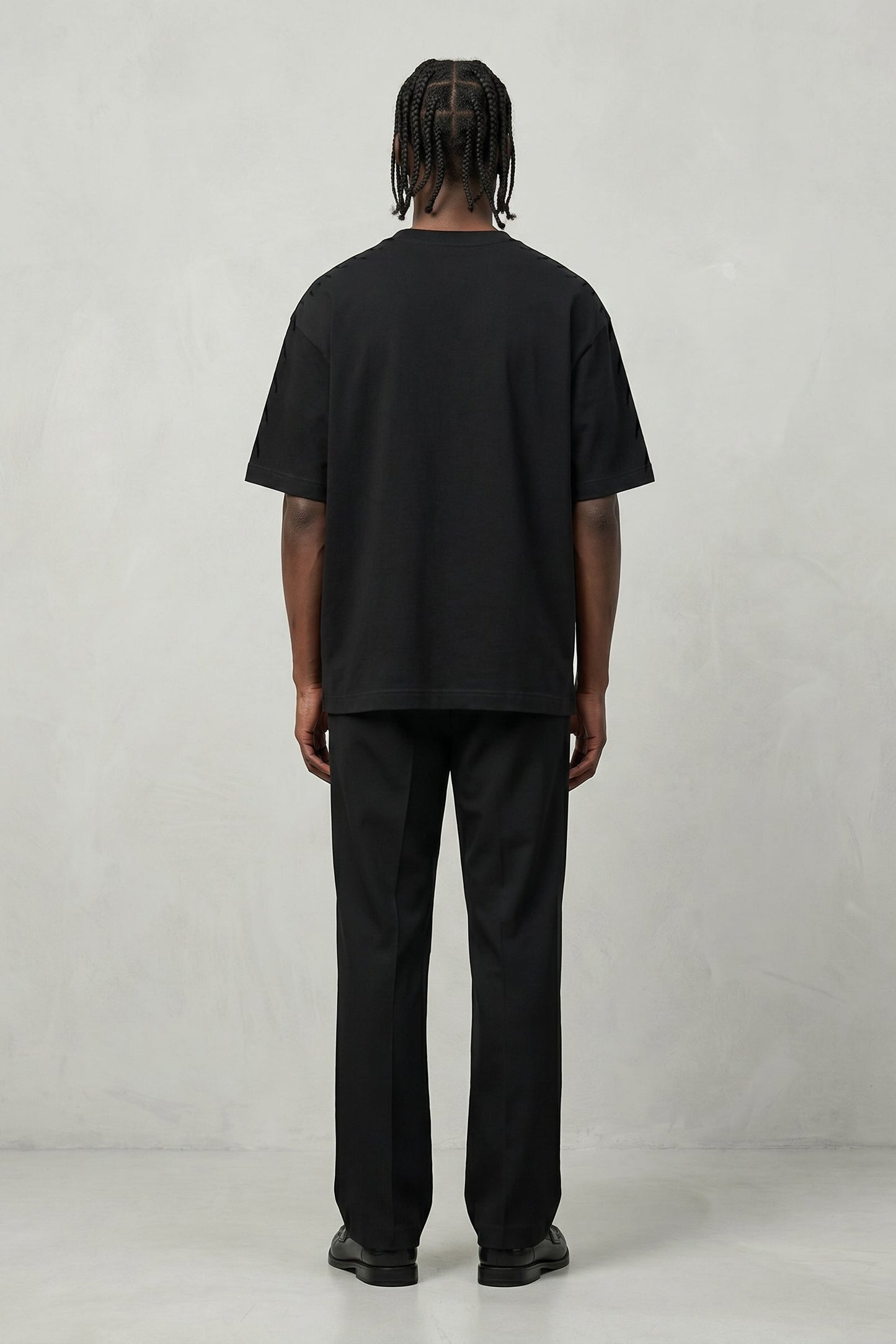 Person wearing a black t-shirt and pants on a plain background