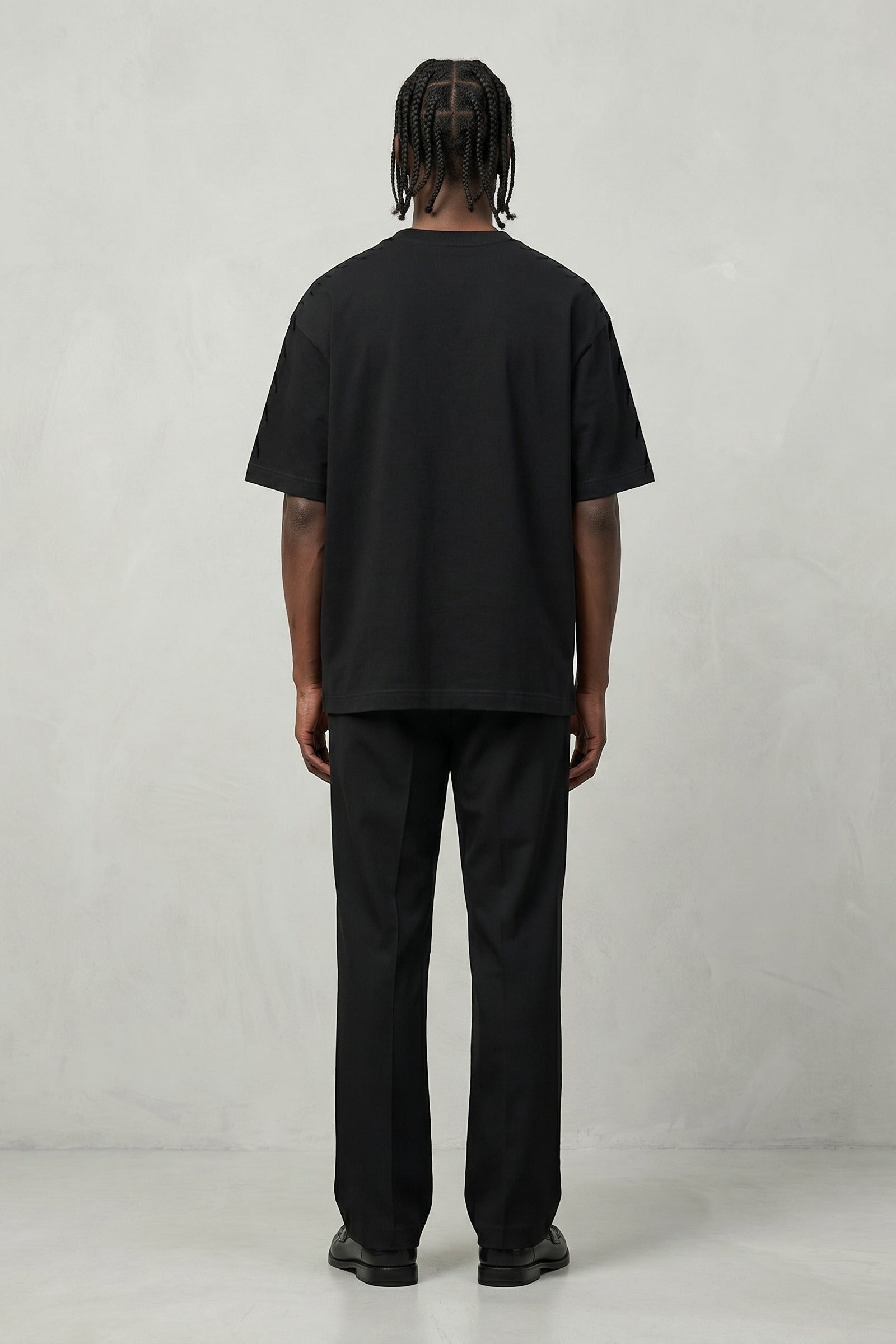 Person wearing a black t-shirt and pants on a plain background