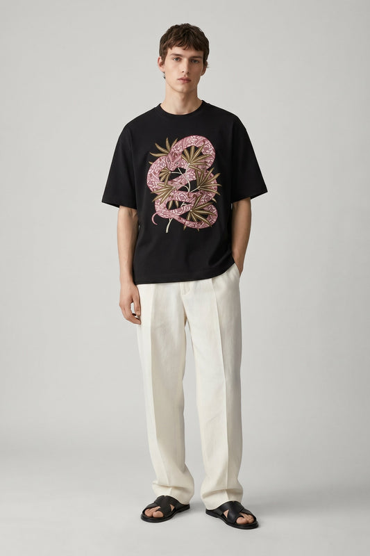 Person wearing a black t-shirt with a pink and green graphic design on a plain background