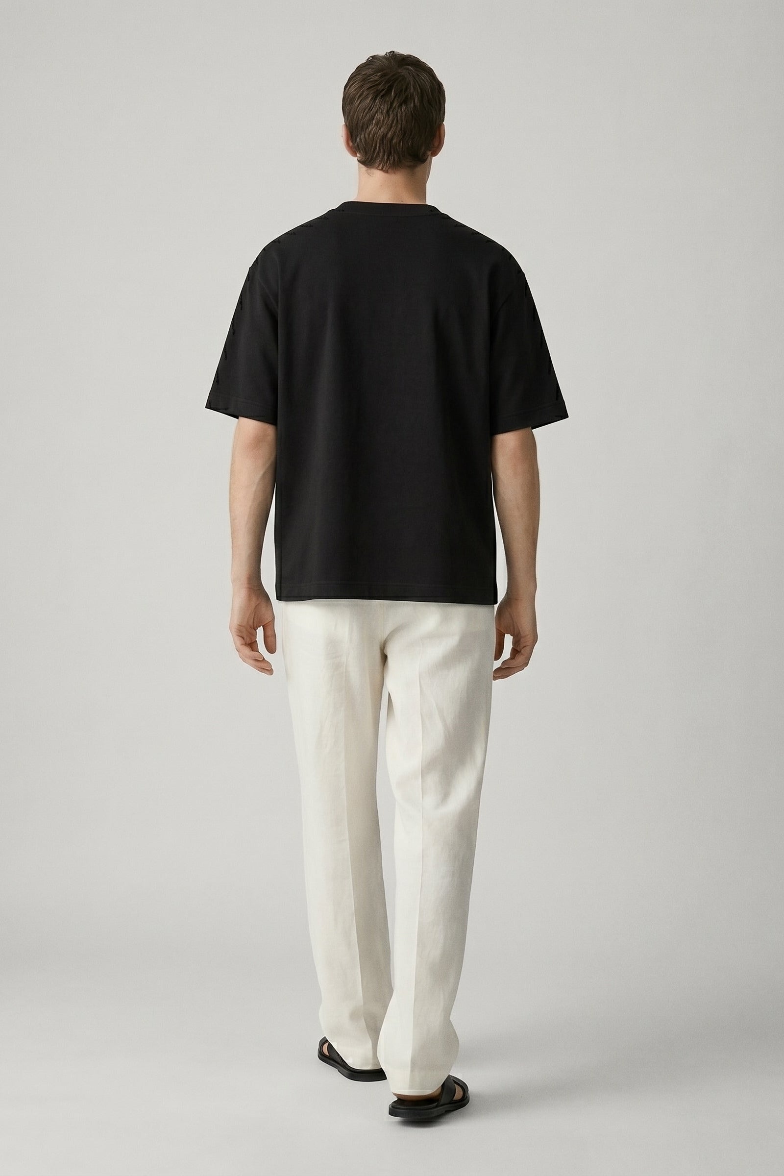 Person wearing a black t-shirt and white pants on a plain background