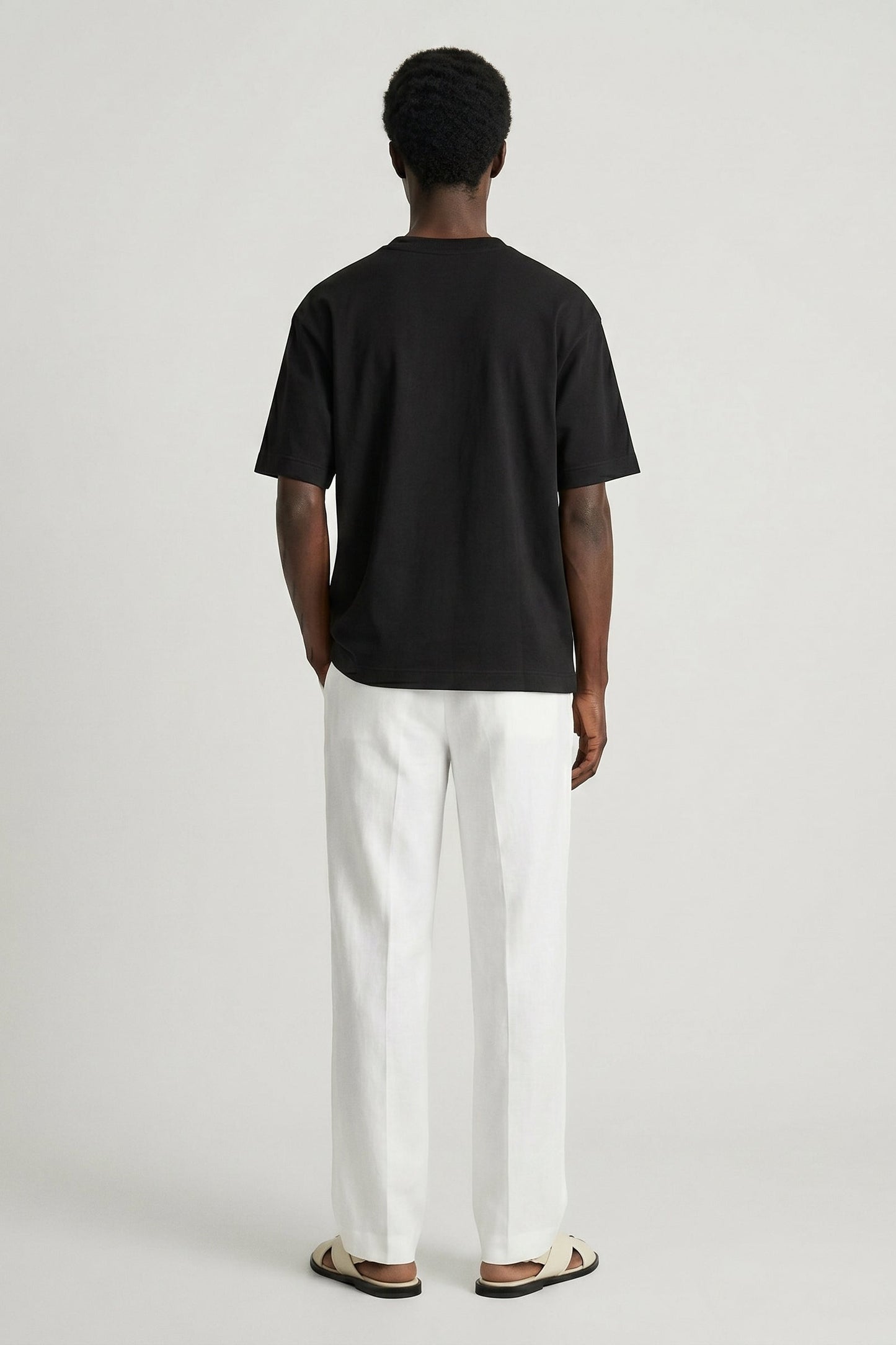 Person wearing a black t-shirt and white pants on a plain background