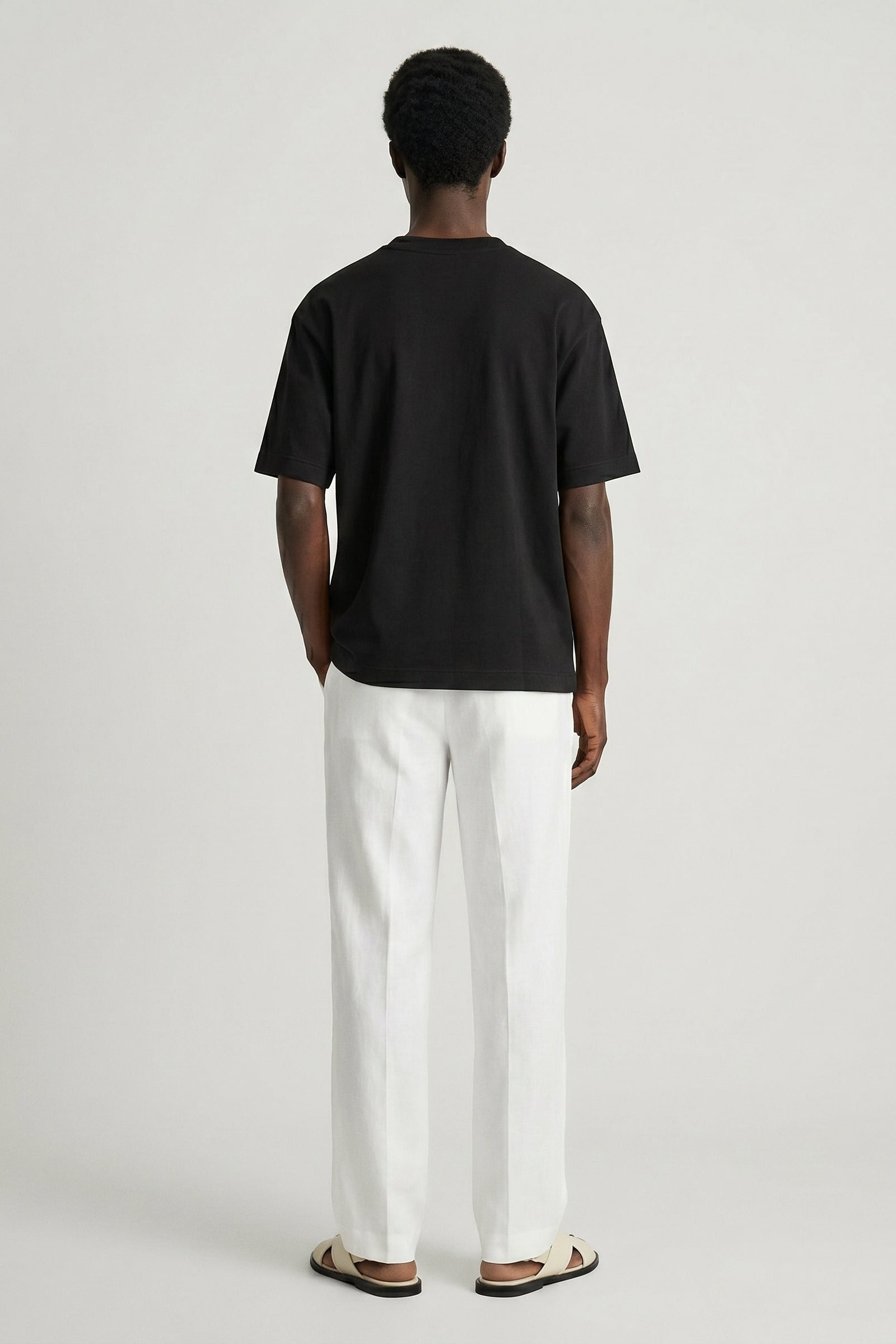 Person wearing a black t-shirt and white pants on a plain background