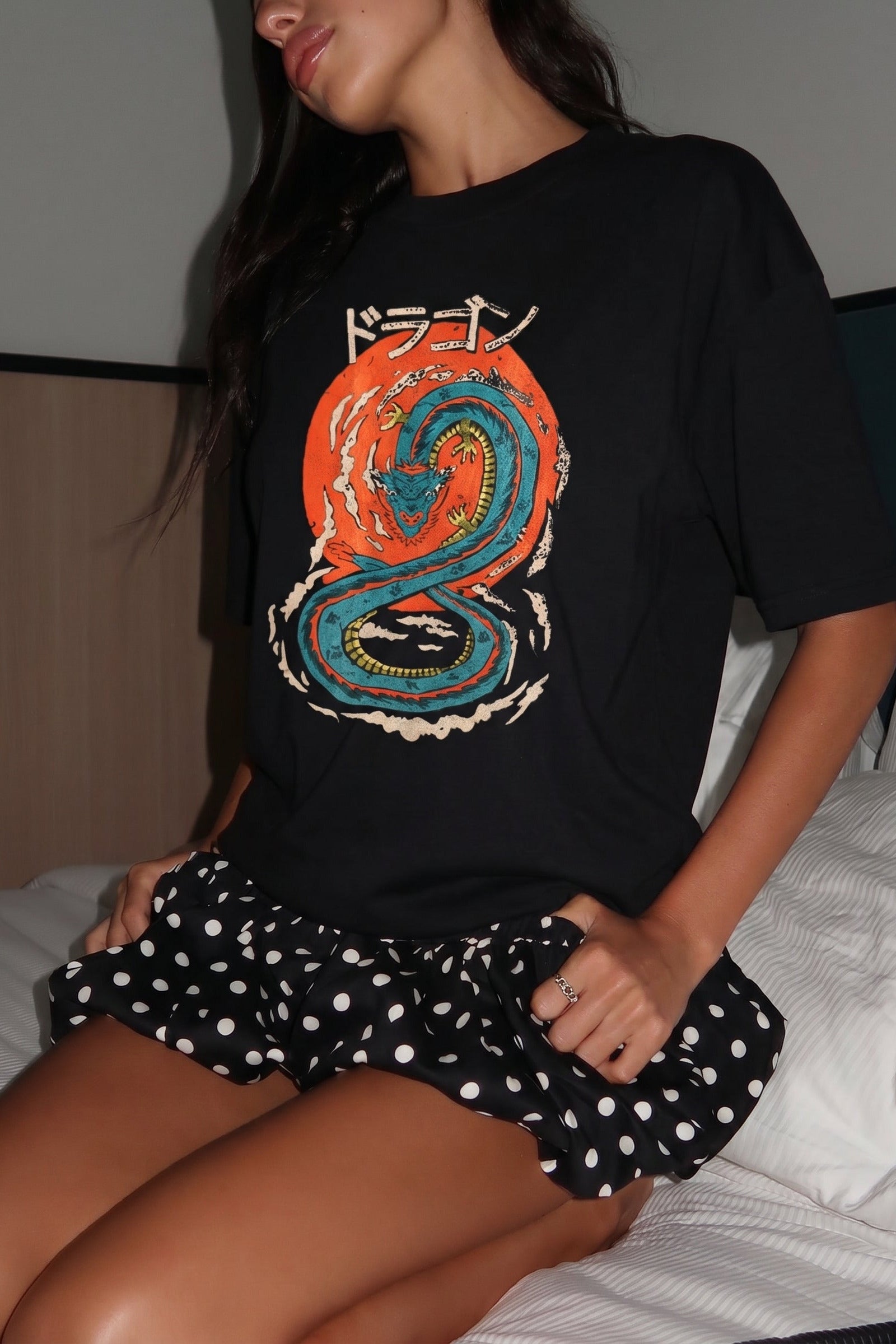 Person wearing a black t-shirt with a colorful dragon design and a polka dot skirt.