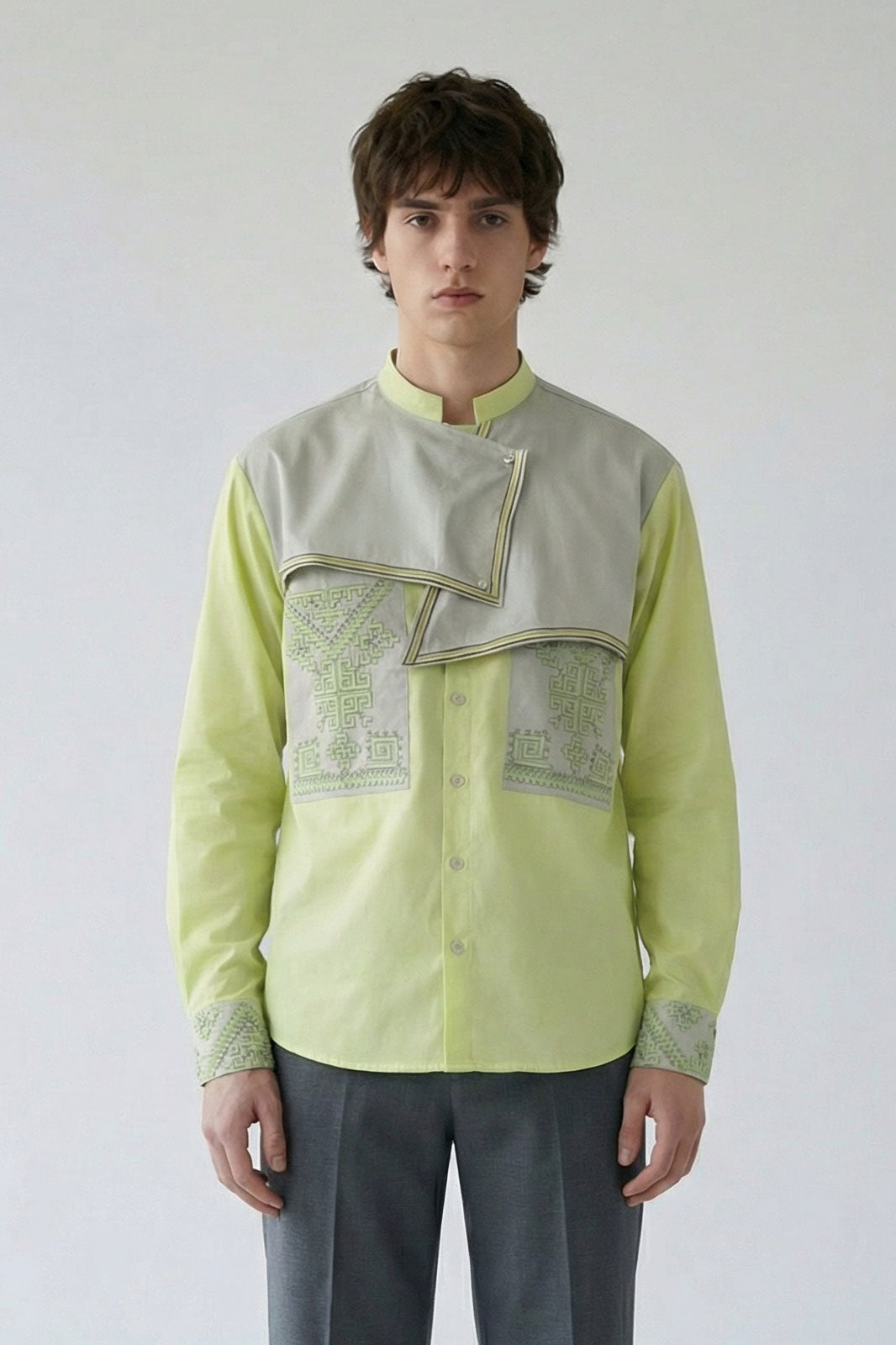 Man wearing a light green shirt with embroidery on a plain background