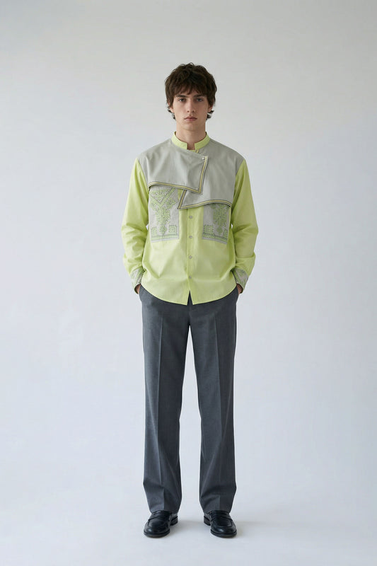 Person wearing a light green shirt with a textured pattern and gray pants on a white background