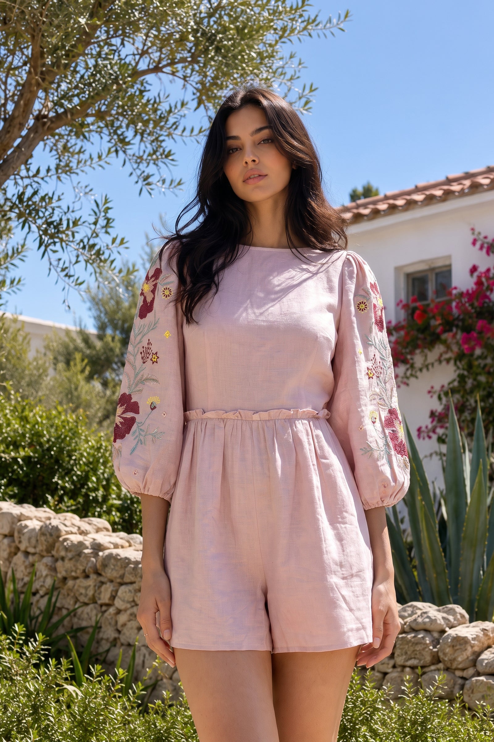 Woman wearing a pink outfit with floral embroidery in an outdoor setting