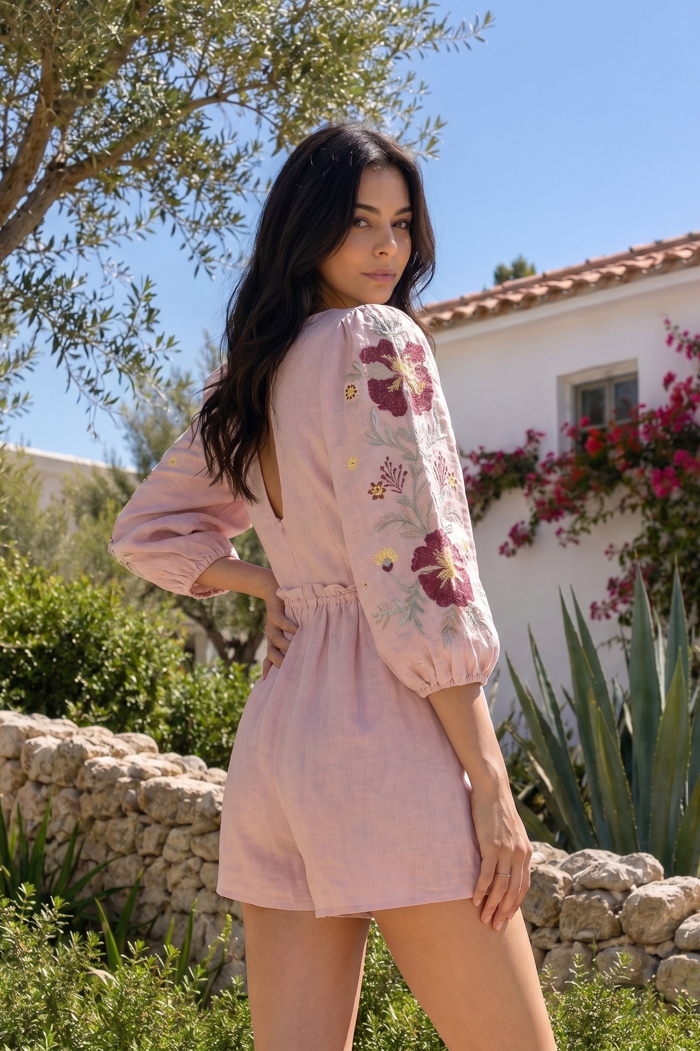 Woman wearing a pink embroidered outfit in a garden setting