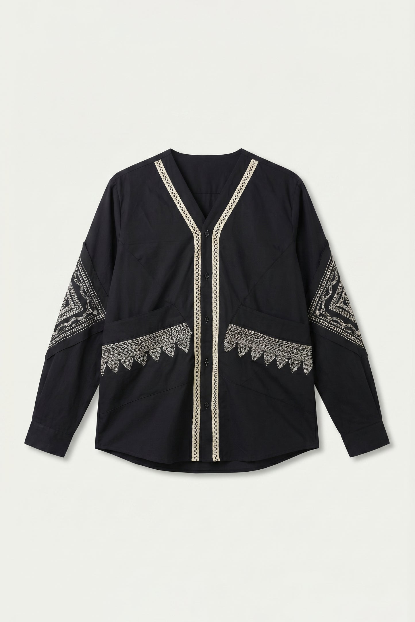 Black long-sleeve top with intricate white patterns on a light gray background
