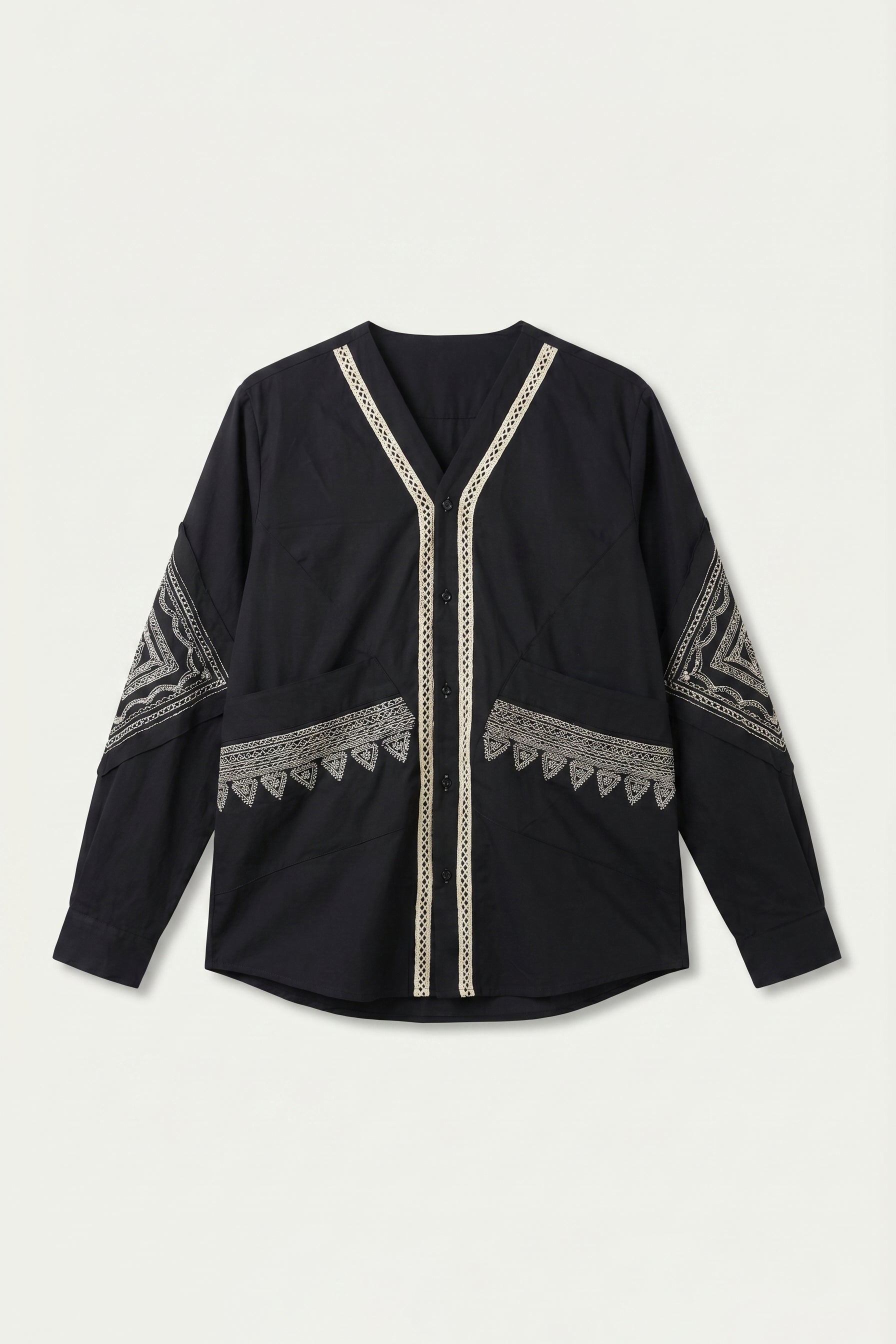 Black long-sleeve top with intricate white patterns on a light gray background