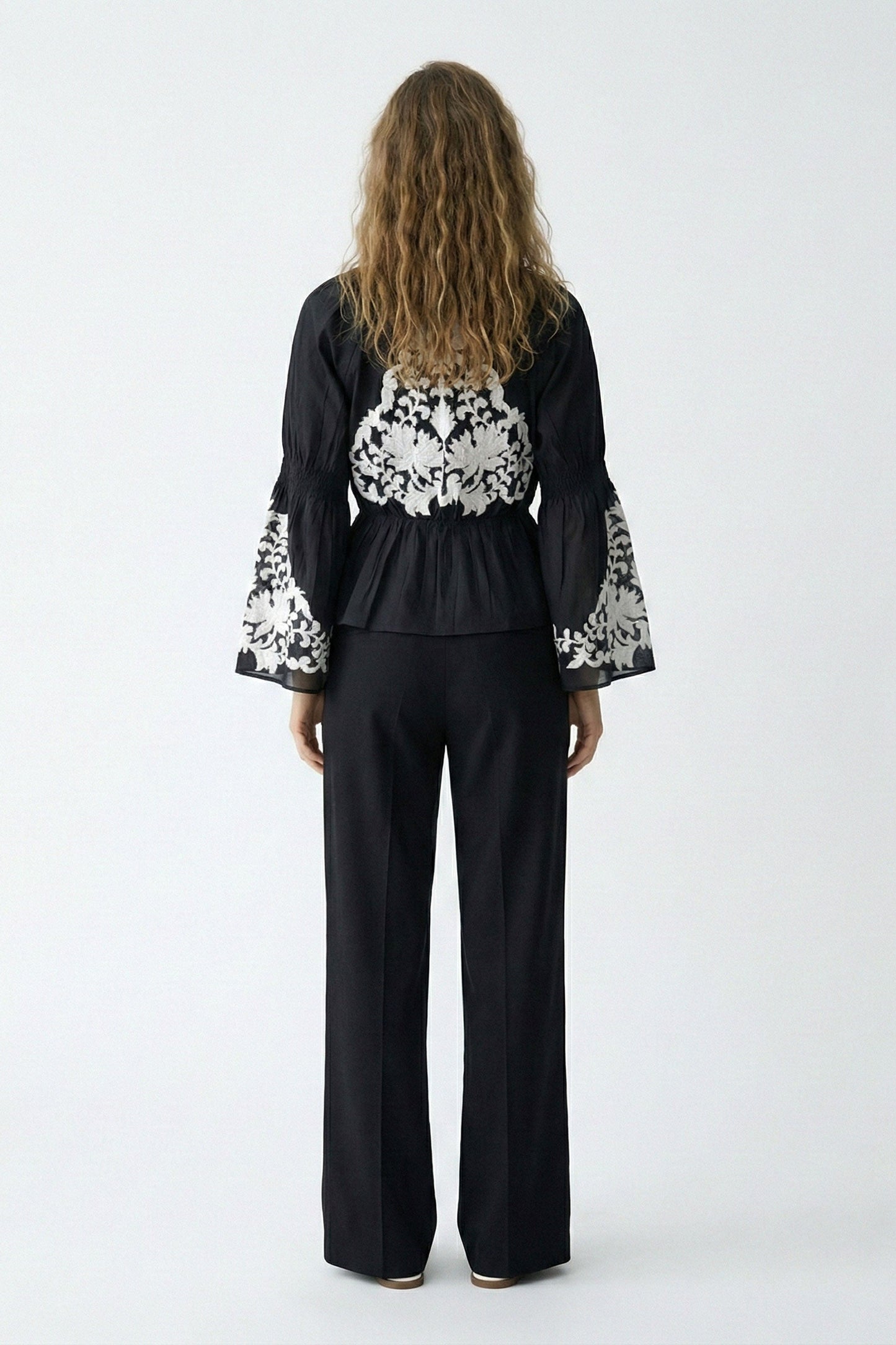 Woman wearing a black outfit with floral patterns on a white background