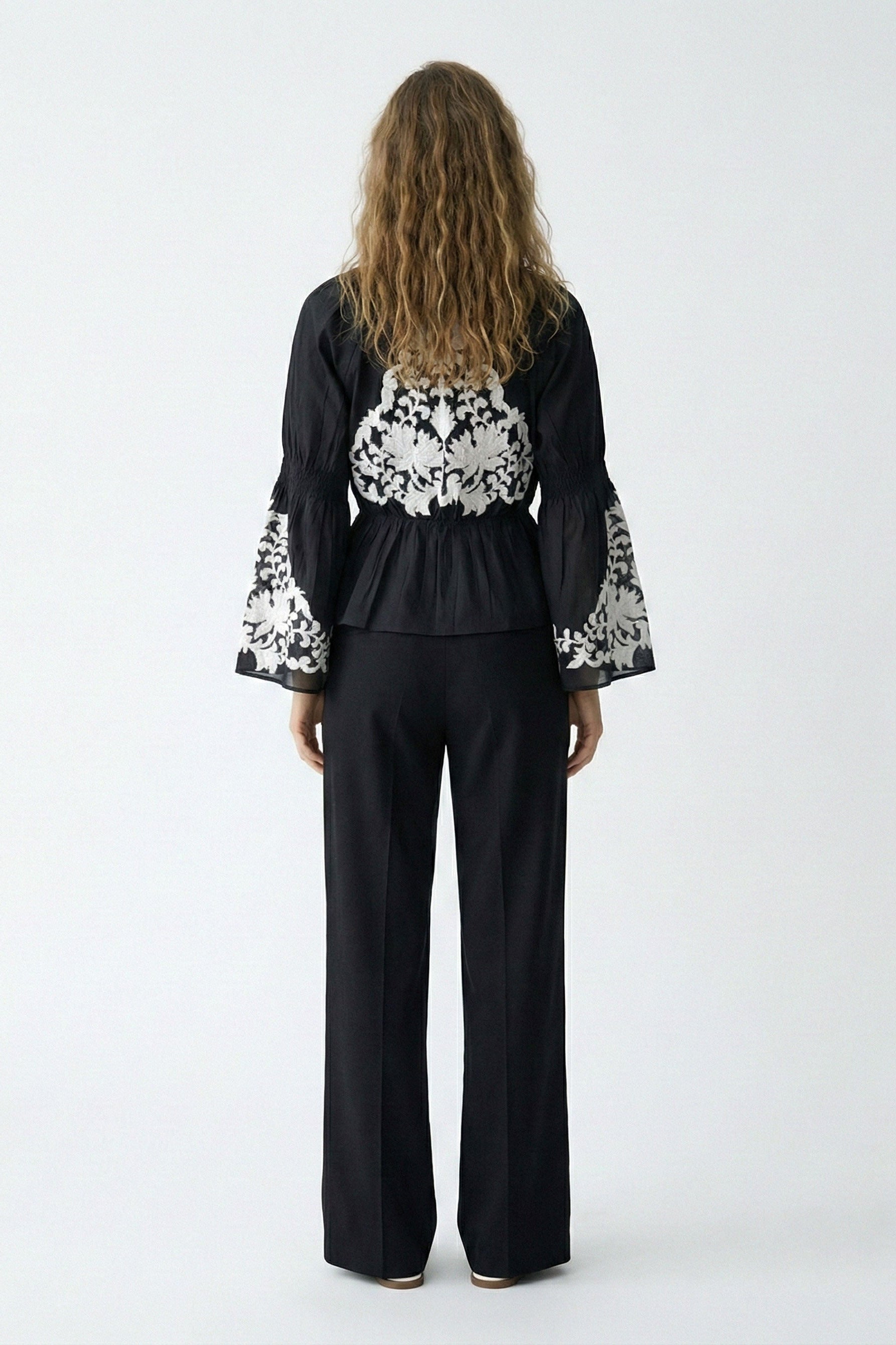 Woman wearing a black outfit with floral patterns on a white background