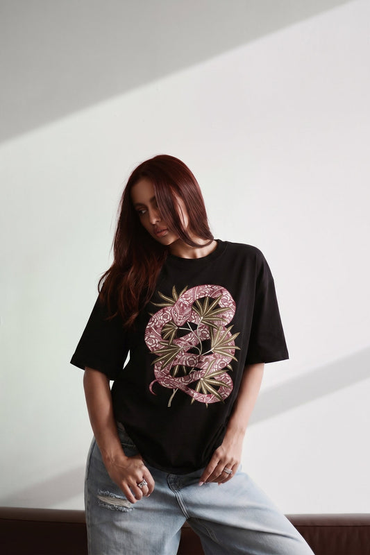 Person wearing a black t-shirt with a pink and green graphic design on a white background