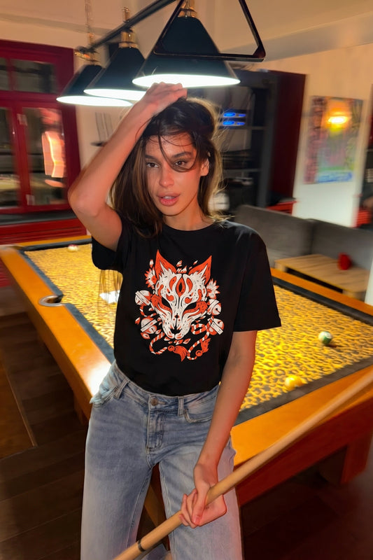 Person wearing a black t-shirt with a fox design in a pool hall.