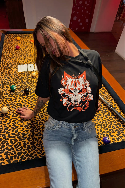 Person wearing a black t-shirt with a fox design in front of a pool table with a leopard print felt.