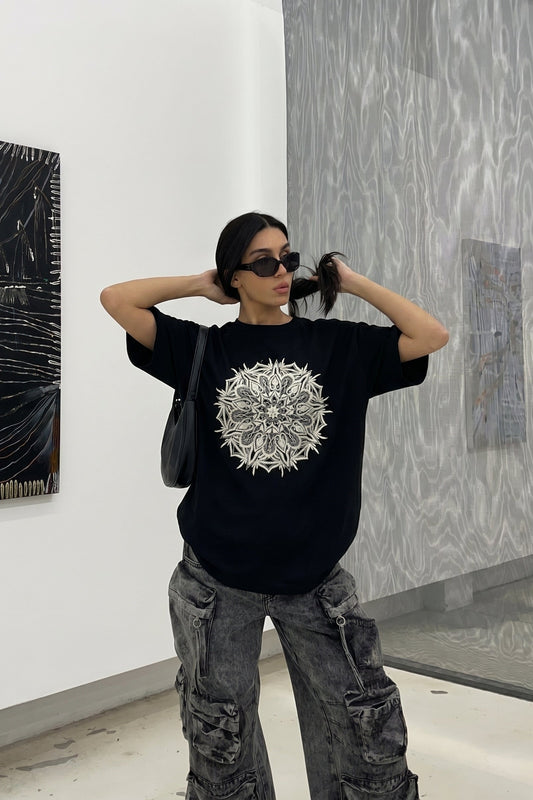 Person wearing a black t-shirt with a white design in an art gallery.
