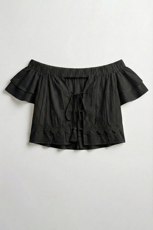 Black off-shoulder top with ruffled details on a light gray background