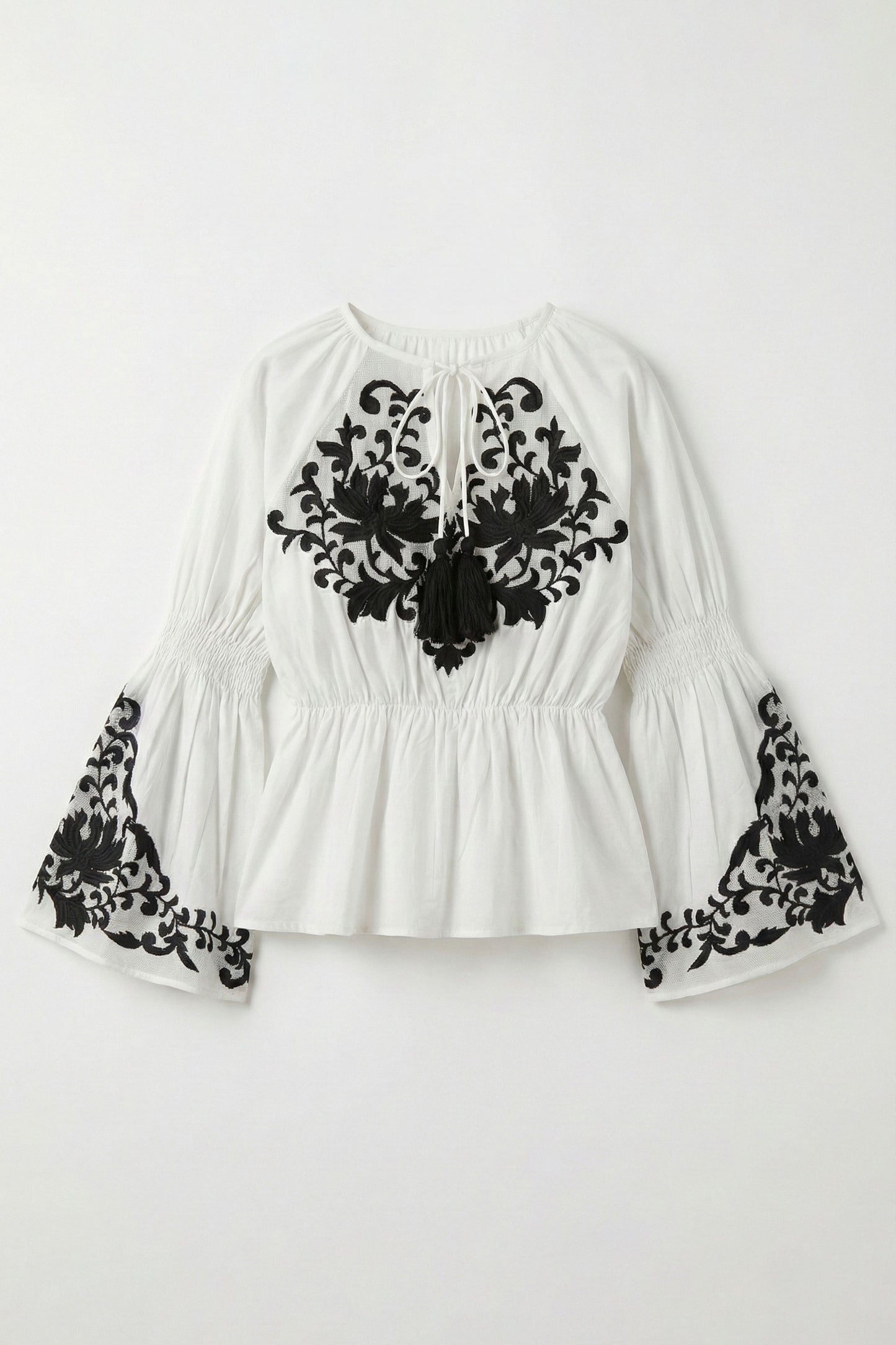 White blouse with black lace details on a white background