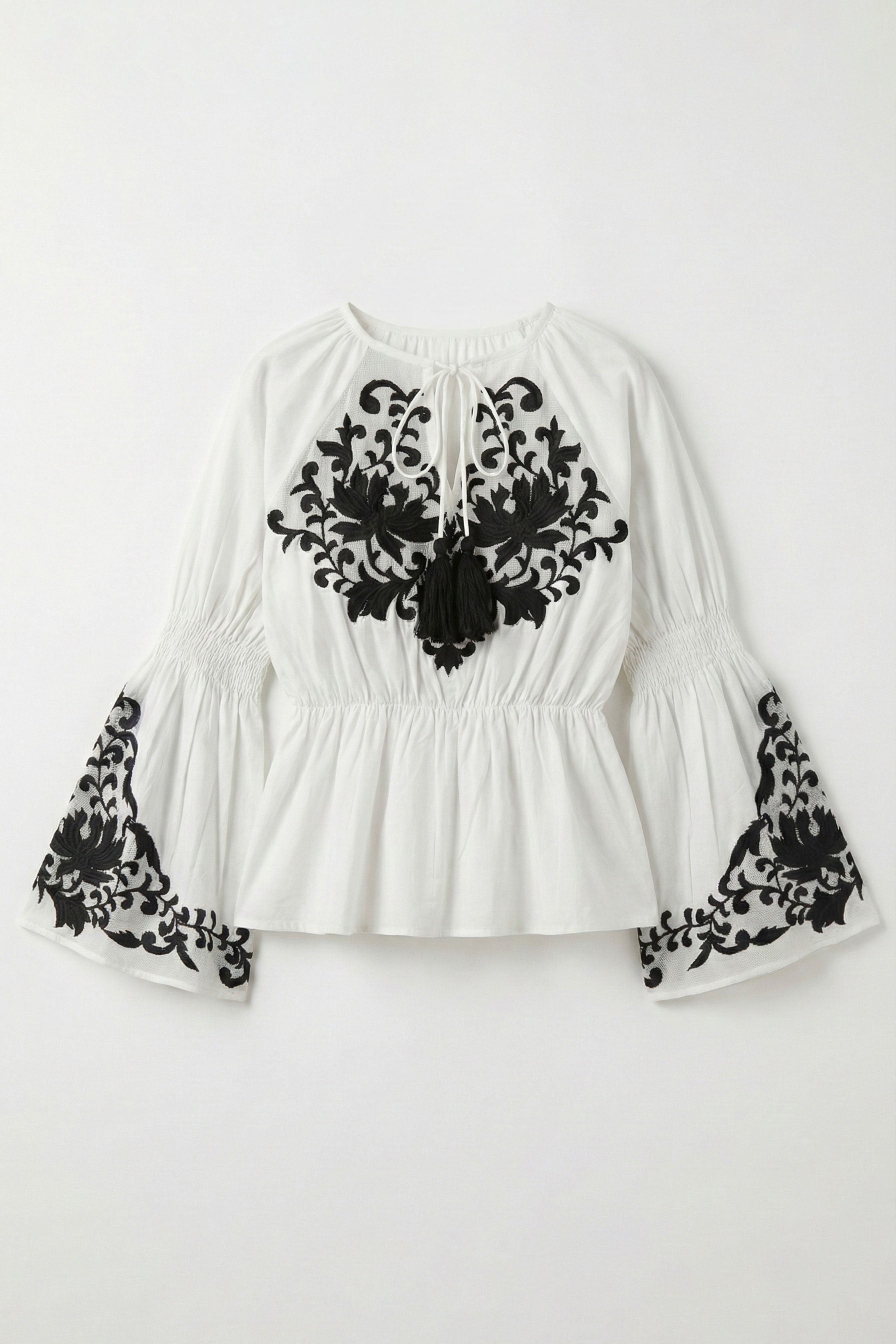 White blouse with black lace details on a white background