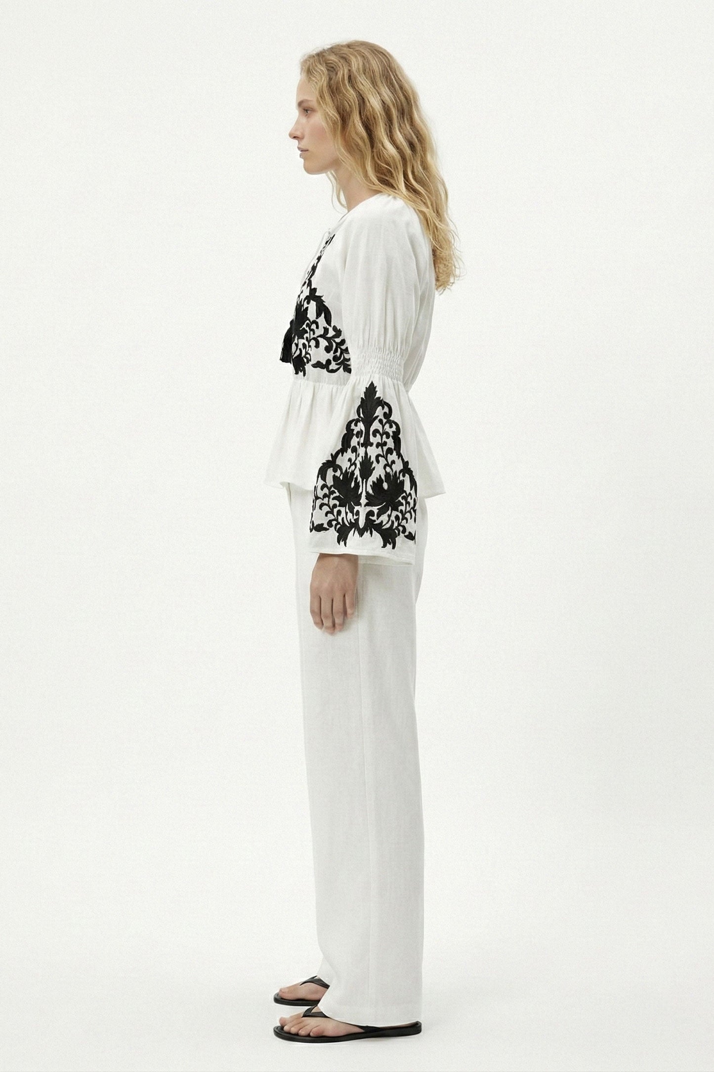 Woman wearing a white outfit with black floral patterns on a white background