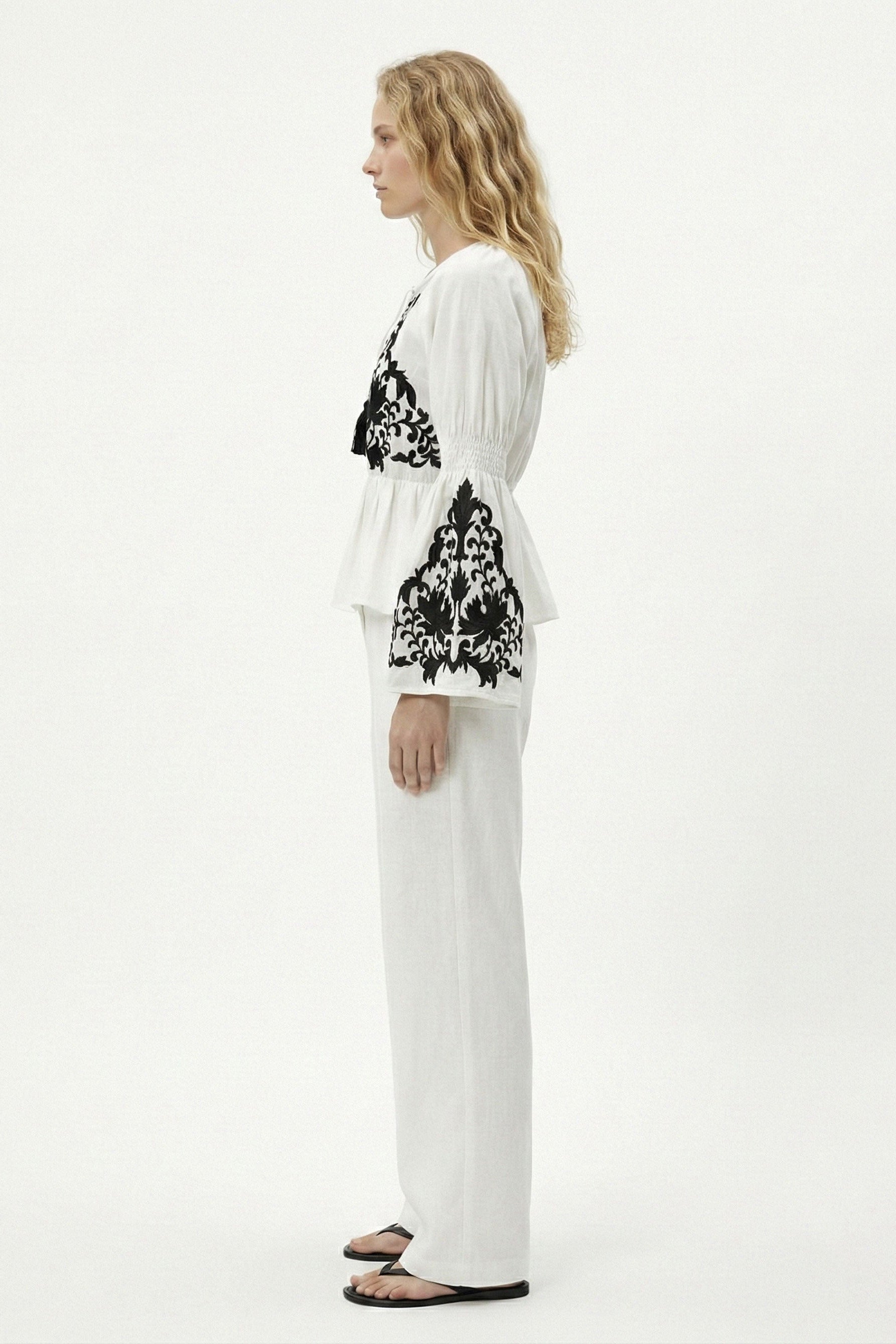 Woman wearing a white outfit with black floral patterns on a white background